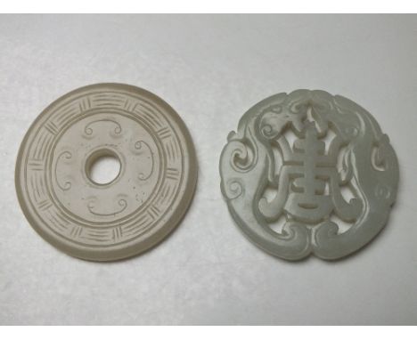 A CHINESE CELADON JADE CARVED AND PIERCED CIRCULAR PENDANT, with central character mark, Dia. 5.7 cm, together with a circula