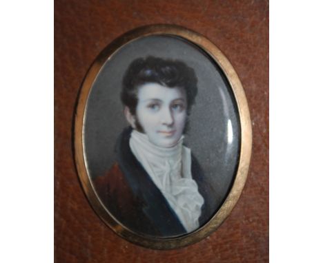 A LATE 19TH / EARLY 20TH CENTURY OVAL PORTRAIT MINIATURE OF A YOUNG GENTLEMAN IN BLUE COAT WITH A RED COLLAR, with gilt metal
