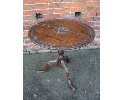 A 19TH CENTURY OAK CARVED TILT TOP PEDESTAL TABLE, the circular top with carved detail to the centre and edges, raised on a c