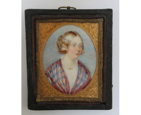 A LATE 19TH / EARLY 20TH CENTURY OVAL PORTRAIT MINIATURE OF A LADY IN A TARTAN SHAWL, in a leather frame, unsigned, framed an
