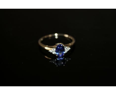 A HALLMARKED 10K GOLD AAA TANZANITE AND DIAMOND RING, the central oval tanzanite being approx 1.65 carats, ring size R to S