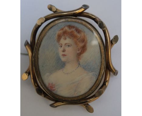 A LATE 19TH / EARLY 20TH CENTURY OVAL PORTRAIT MINIATURE OF A LADY HOLDING A PINK FLOWER, in an oval decorative gilt metal br