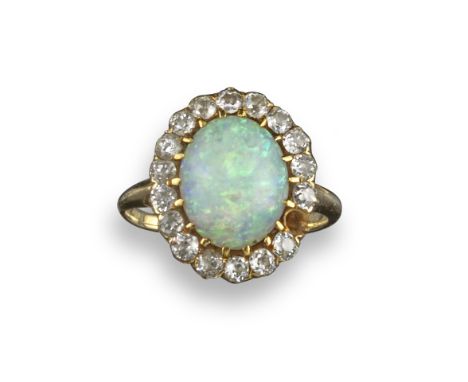 An opal and diamond cluster ring, the oval-shaped opal set within a surround of old circular-cut diamonds (one missing) in ye