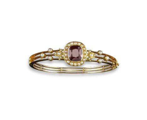 An Edwardian garnet and seed pearl bangle, the cushion-shaped garnet is set within a surround of seed pearls in yellow gold, 