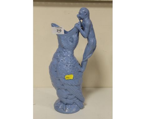 AN UNUSUAL BLUE CERAMIC JUG IN THE FORM OF A MONKEY PEERING INTO A LARGE BIRDS BEAK HEIGHT- 33CM