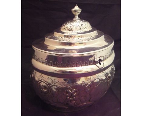 A George III silver tea caddy of bellied oval form with later embossed floral decoration, bearing initialled cartouche to cen