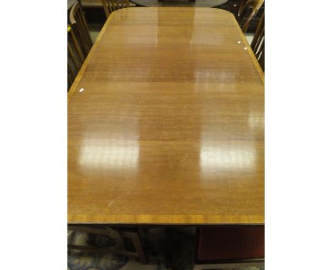 A 20th Century mahogany dining table in the Regency taste, the rounded rectangular top cross banded and with reeded edge and 