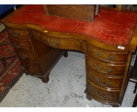 A modern reproduction figured walnut shaped front desk with central serpentine drawer flanked by two banks of four bow-fronte