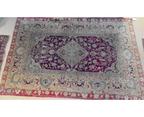 A Persian carpet, the central panel set with a diamond shaped medallion on a red ground with stylised floral decoration, with