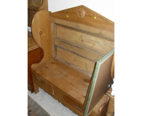 A pine settle with architectural shaped pediment, shaped sides, two drawers to the seat and shaped apron