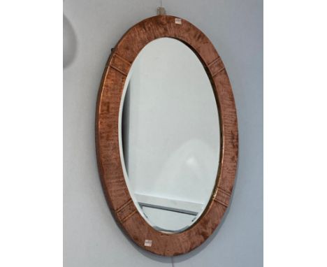 An Arts and Crafts hammered copper oval Mirror, with beveled glass, H 52 cm x W 72.5 cm. 