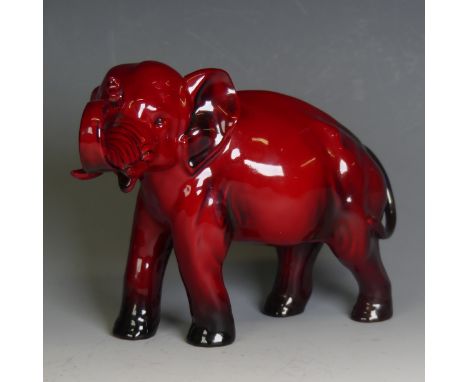 A Royal Doulton red flambe figure of an Elephant, trunk in reared position and blue colouration to tail, signed Noke to front