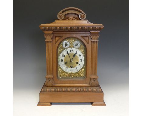 An early 20th century German chiming Mantel Clock, in an architectural carved walnut case, the brass dial with scroll spandre