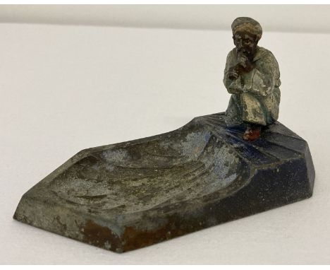 A vintage cold painted Austrian metal ashtray with Arabic gentleman playing a pipe.   Approx. 11.5 cm long x 7 cm tall.