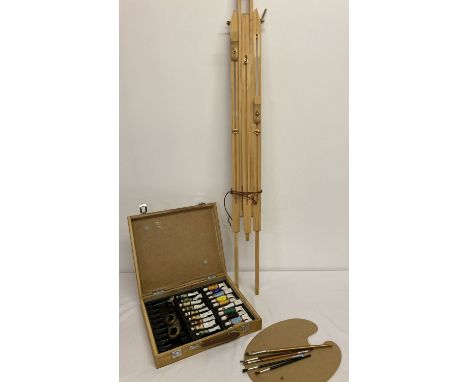 A wooden cased artists box of paints, brushes and pallet together with a large wooden tripod easel.  