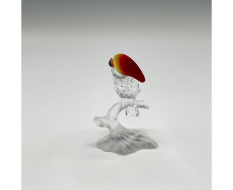 This colorful figural is perched on a frosted crystal branch looking out with orange and blue crystal eyes and pointing with 