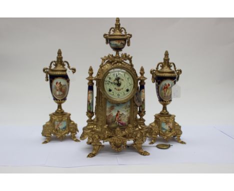 A gilt metal mantle clock with garniture, transfer printed decoration to ceramic inserts, clock having enamelled dial with Ar