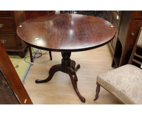 A George III mahogany tilt top tripod table; The circular top being made from one piece of timber, turned column, three cabri