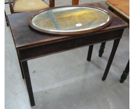 An oval bevel glass wall mirror together with a folding games table on shaped square legs with inner beize playing surface