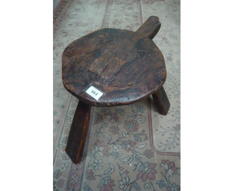 A 19th century elm three legged stool of primitive construction, 29cm high