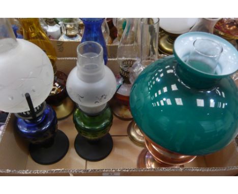 Eight coloured glass reservoir oil lamps with chimneys together with copper lamp with shade and chimney