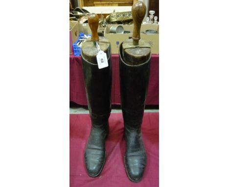 A pair of black hunting boots with wooden trees
