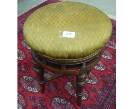 An adjustable circular stool on four splayed legs
