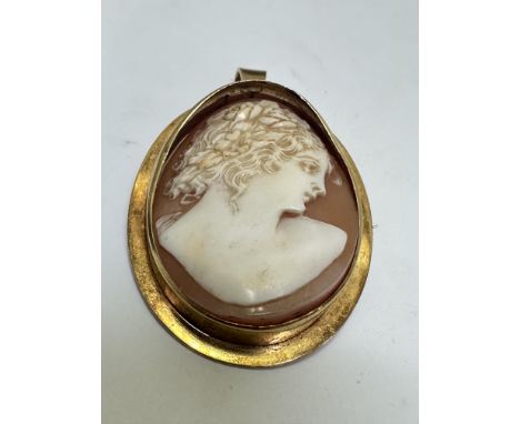 A 18ct gold set oval cameo brooch/pendant, the shell carved cameo depicting a portrait of a young lady with flowers in her fl