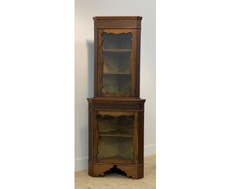 An Edwardian walnut two part corner cabinet in the Chippendale taste, with blind fret to freize and canted sides enclosed two