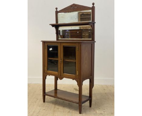 An Edwardian walnut side cabinet, the sectional bevel glazed mirror back with open shelf above two glazed doors enclosing an 