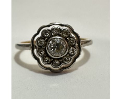 A Edwardian 18ct gold and platinum diamond cluster ring, the central old cut stone mounted in rub over setting with a surroun