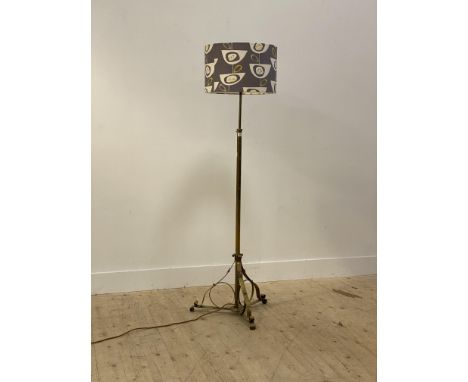 An early 20th century brass telescopic standard light, the octagonal post raised on three scrolled and splayed supports with 