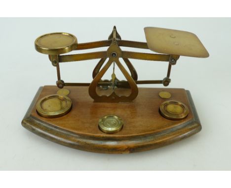 Small set of early 20th century brass postal scales and weights on wooden base. 20cm.