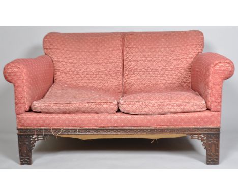 A mahogany two seat sofa, with Chippendale style blind fretwork legs and frame, upholstered in a pink fabric, with two cushio