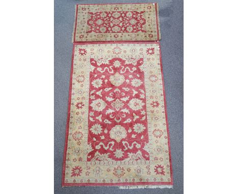 A Turkish style carpet and a matching rug, with central claret panel with scrolling floral motifs within a similarly decorate