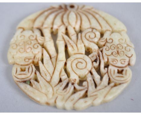 A pale jade circular carved pendant carved with frogs below palm trees and foliage 6.5cmD