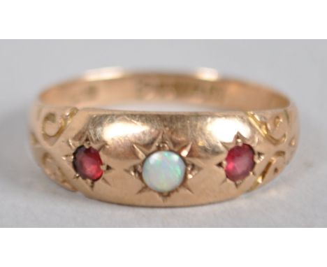 A yellow metal ring principally set with a cabochon cut opal and flanked by two synthetic rubies. Hallmarked 9ct gold, Cheste