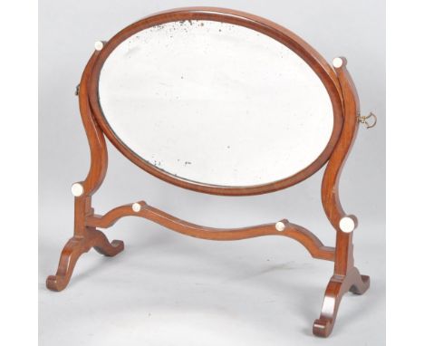 A George III mahogany oval swing frame dressing table mirror, the cushion shaped frame, with scroll stretcher and feet inlaid