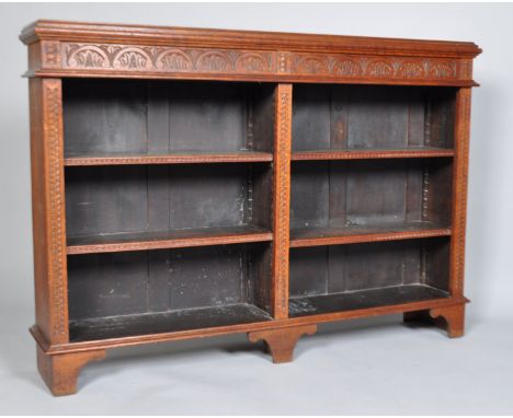 A carved oak bookcase of rectangular section with two divisions and four adjustable shelves, the frieze carved with stylised 