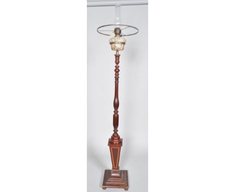 An oil lamp with mottled glass reservoir raised on a mahogany baluster turned stem on a satinwood inlaid tapered base on foot