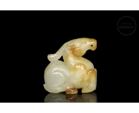Small carved jade, light toned, with reddish and amber spots. It shows an animal, similar in shape to a goat, lying on its fo