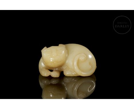 A light-coloured carved jade figure with golden flecks and patina produced by antiquity. It shows an animal resting, with its