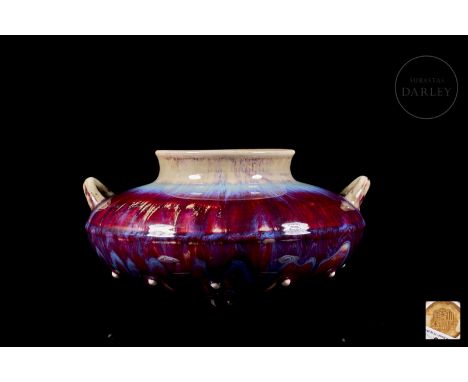 Ceramic vessel placed on three small rounded feet. It has a flat body with a circular plan, adorned by a succession of small 