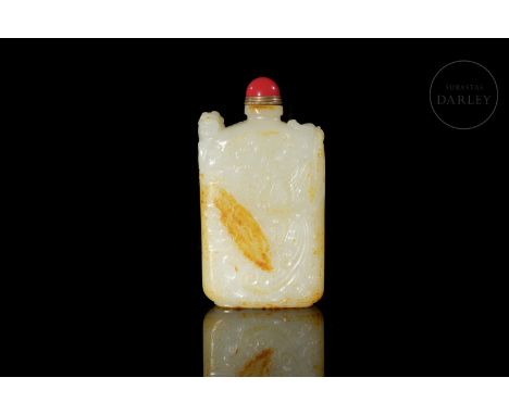 A light-coloured carved jade snuff bottle with reddish and golden flecks. It has a thin rectangular base and an elongated bod