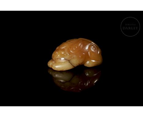 Small carving of reddish jade with red and amber stains. It shows a crouching beast with its body lying on its four legs and 