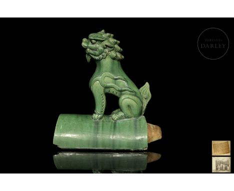 Large fired ceramic tile with a concave and elongated shape, covered with a rich green glaze. At the top, it depicts a foo li