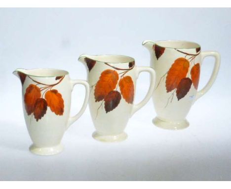 Set of three Wilkinson honeyglaze graduated jugs, painted with autumn leaves