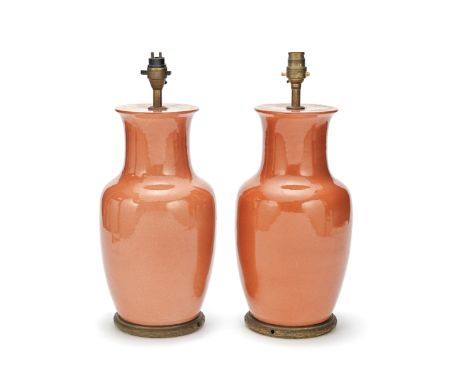 A pair of decorative Chinese style coral glazed ceramic lamps basesthe inverted baluster bodies with flared necks on gilt woo