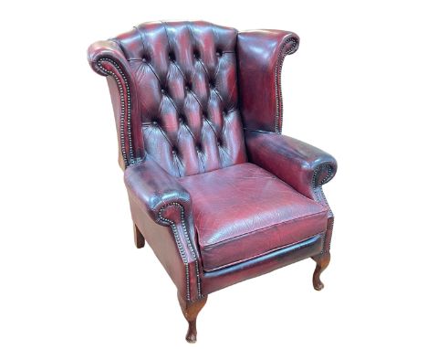 Ox blood leather button backed and brass studded wing armchair.