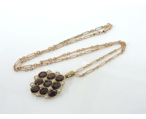 A 9ct gold garnet and seed pearl lozenge shaped pendant, on a fetter and three link chain, marked 9ct